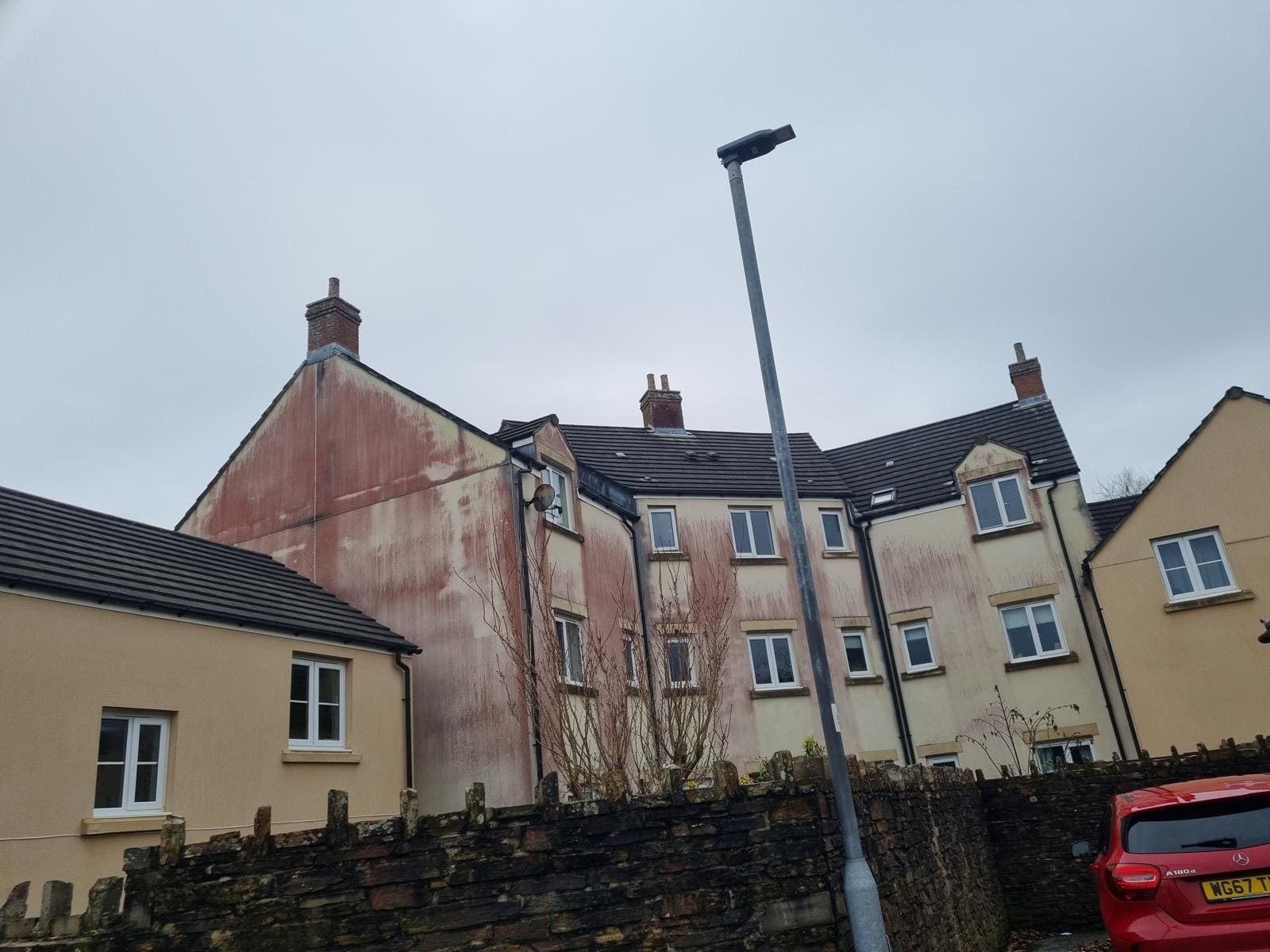 Heavy red algae growth on rendered property before cleaning