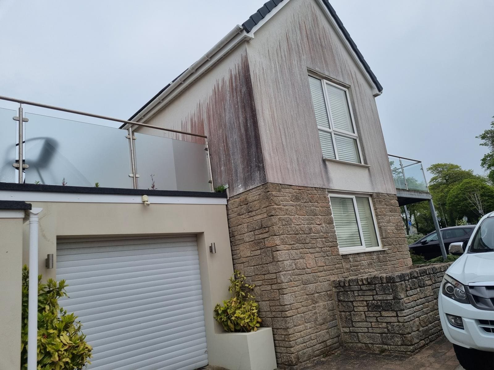 Red algae staining on rendered wall requiring softwash treatment