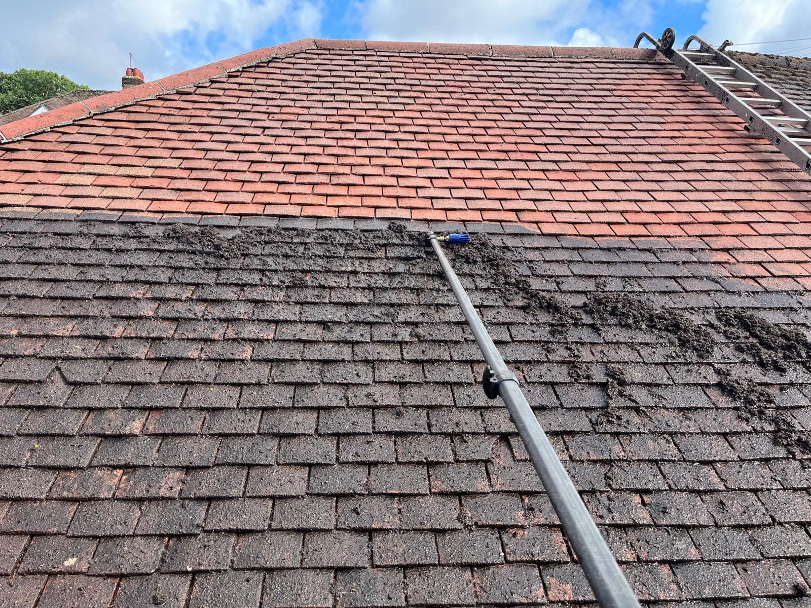 Professional roof cleaning in action with pressure washing equipment